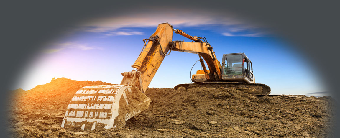 Angled shot of an extended excavator arm over a pile of dirt at sunset