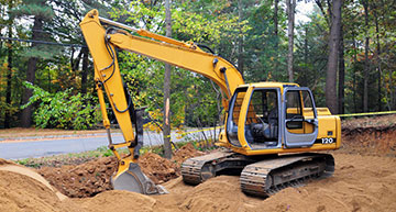 Mini excavator digging along side a residential road | Underground Utilities