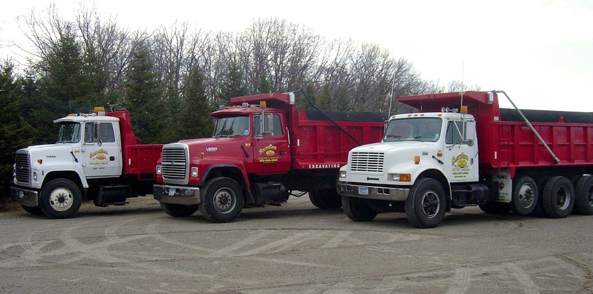 Row of three red and white South Side Sand & Gravel Dump Trucks